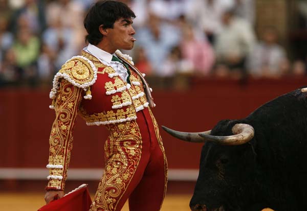Spanish bullfighter Lopez Chaves looks to the crowd in front of a bull during a bullfight in Seville